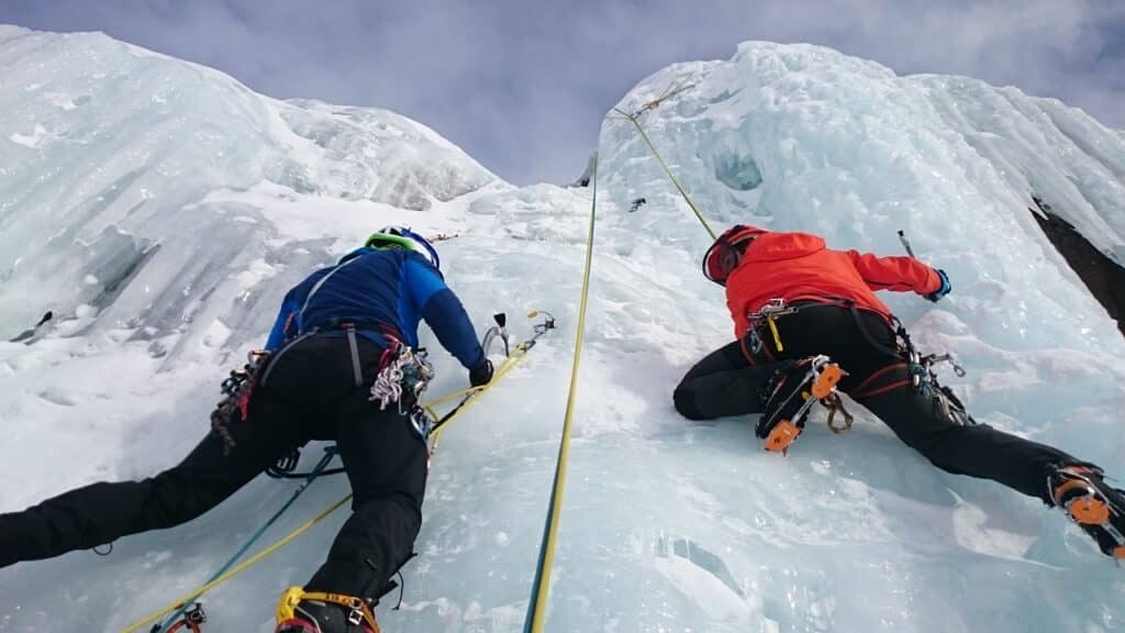 two people seen climbing an ice formation practicing techniques listed in the article ice climbing for beginners