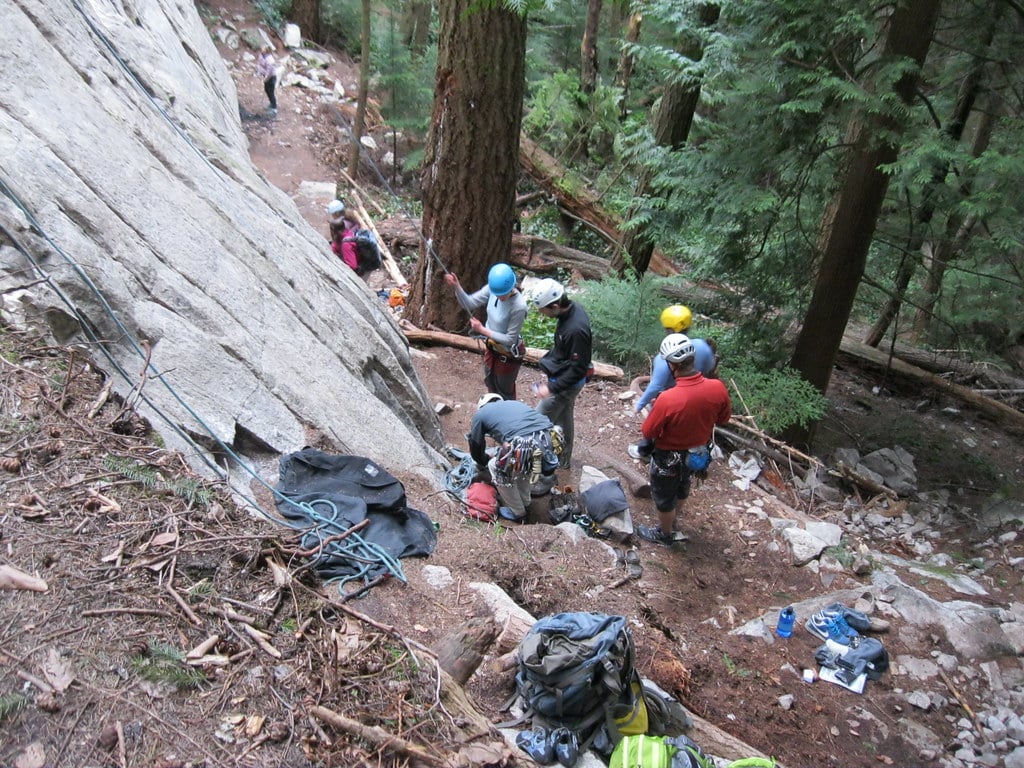 multiple climbers standing at the base of a rock formation with different trad climbing helmets on display