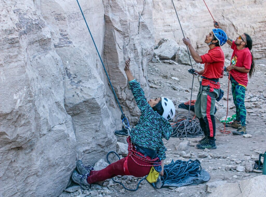 a group of people climbing a rock formation highlighting their trad climbing helmets