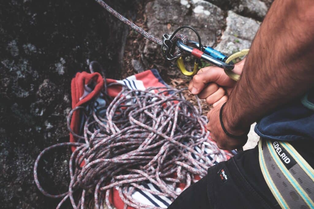 photo showing a man getting trad climbing belay devices ready
