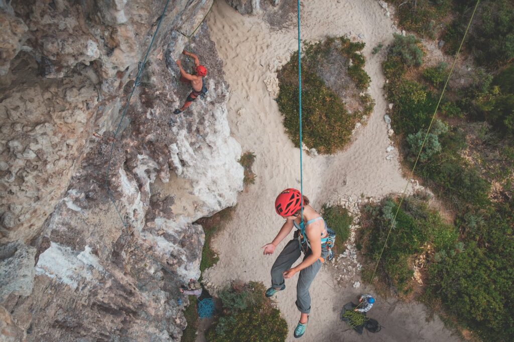 a photo of two people climbing a rock formation utilizing proper communication on their ascent as covered in the rock climbing etiquette article.