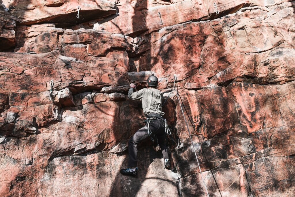 photo of a man climbing a rock face at red rock canyon