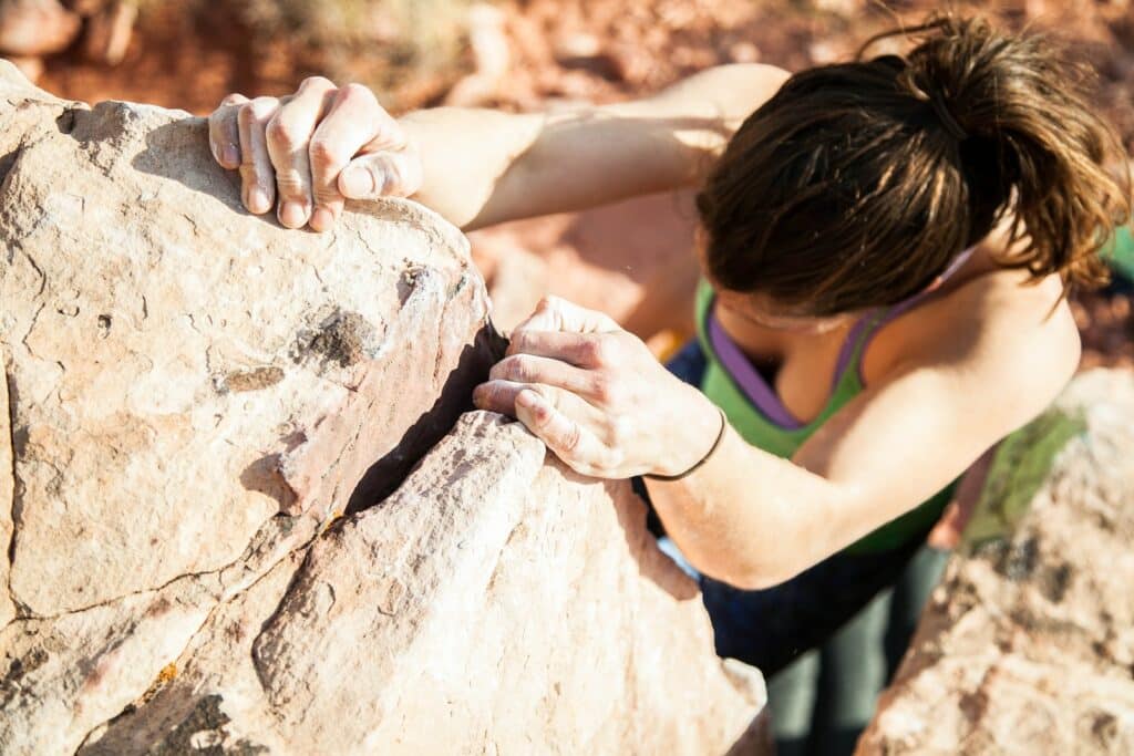 woman practicing bouldering techniques on a climbing route at joshua tree national park. Detailed in the Joshua Tree Climbing Season article.