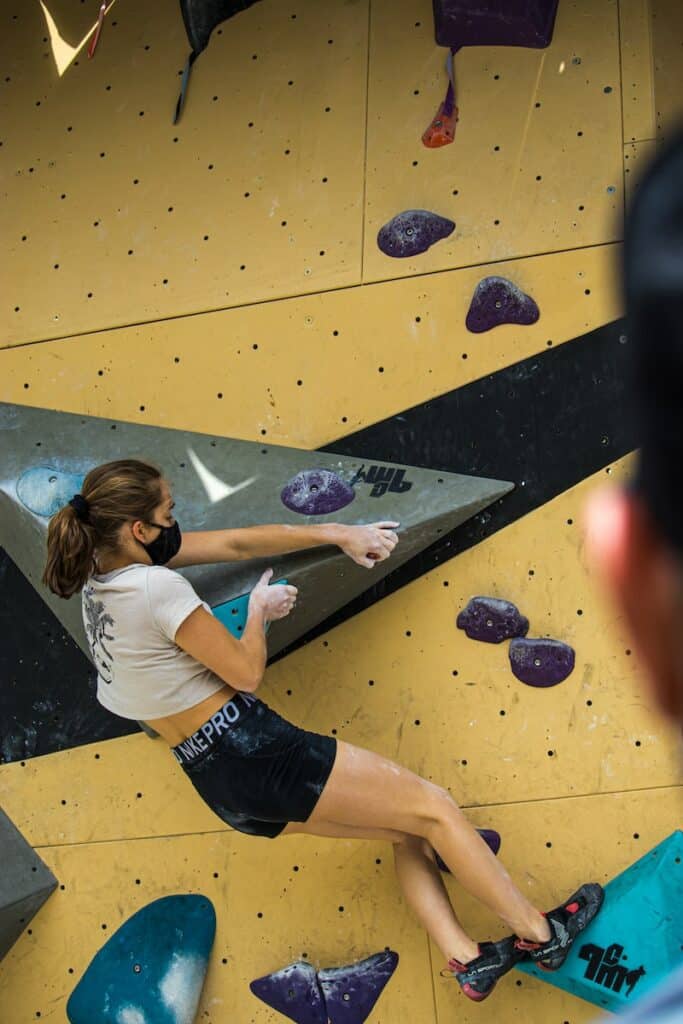 Woman climbing an overhang bouldering wall,  practicing her overhang climbing techniques