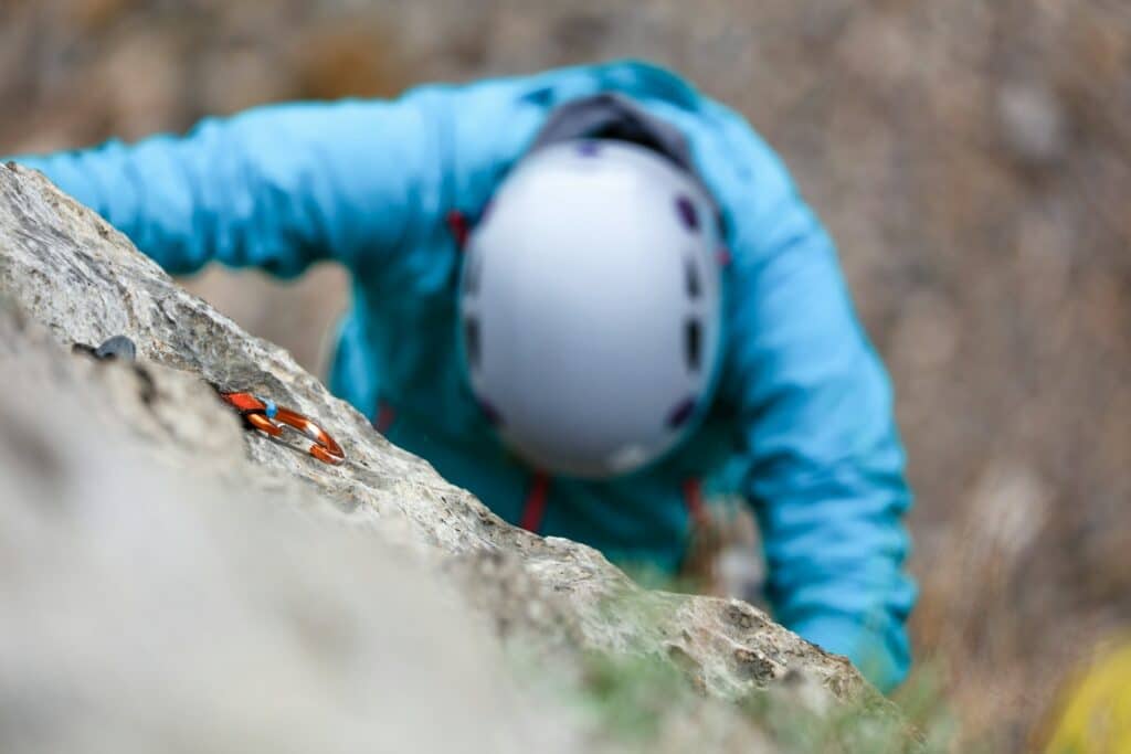 person climbing a rock formation showcasing his trad climbing helmets