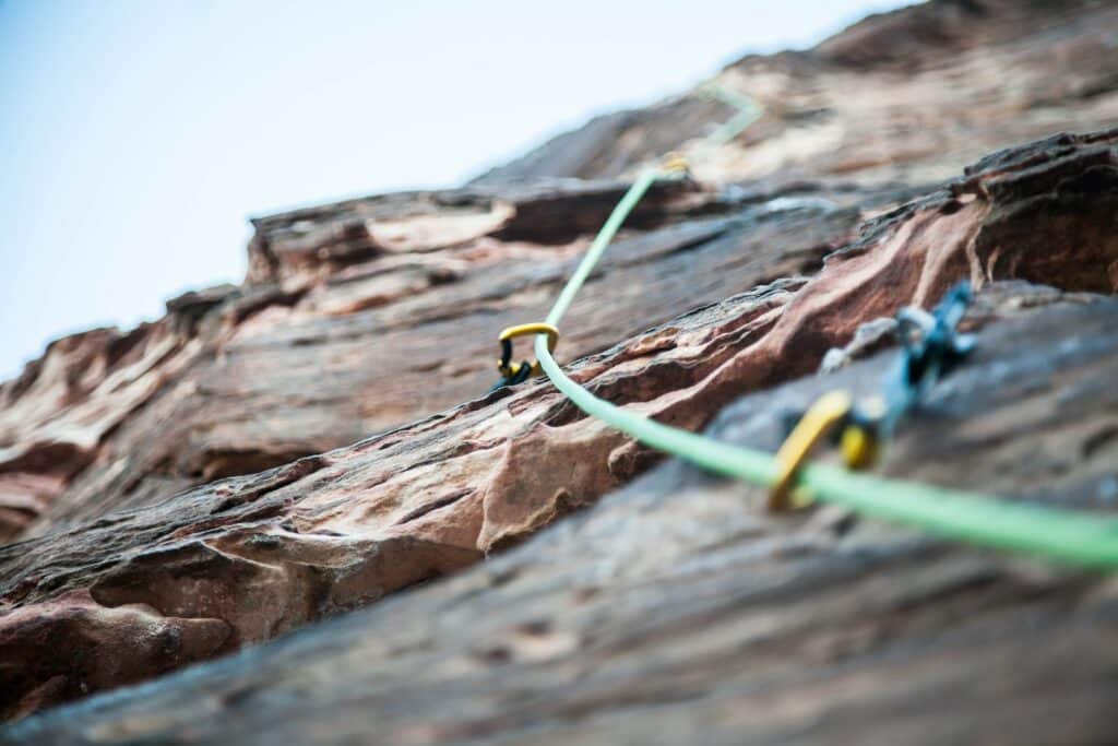 lead climbing on display in rock face, demonstrating trad climbing lead climbing