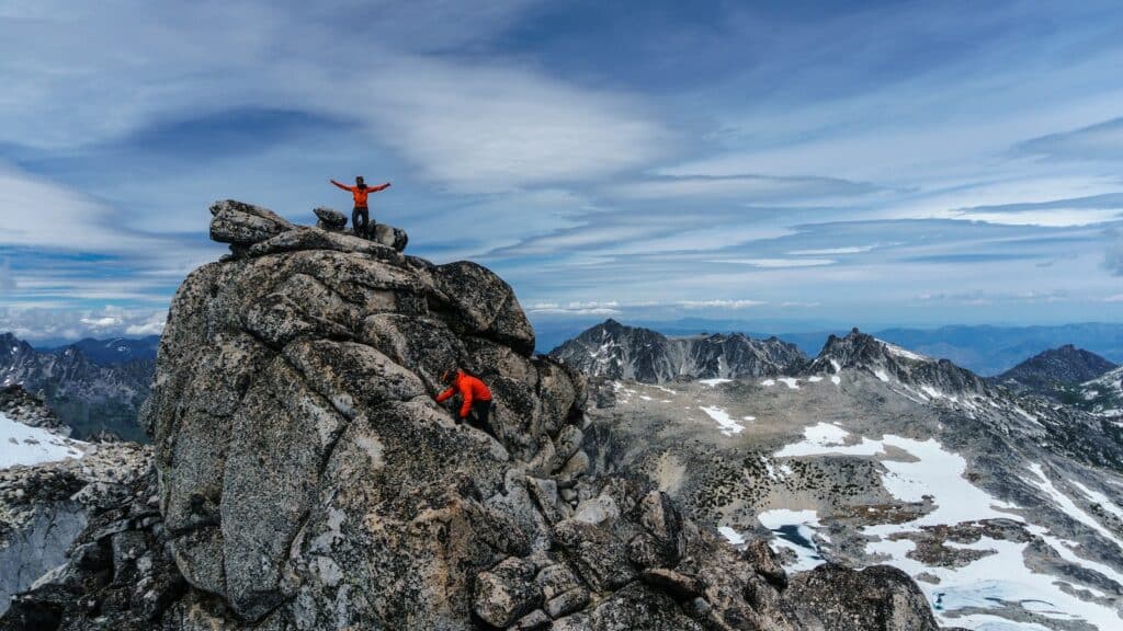 landscape photo of two people climbing and reaching the summit of a rock formation. Pro Rock Climber Interview
