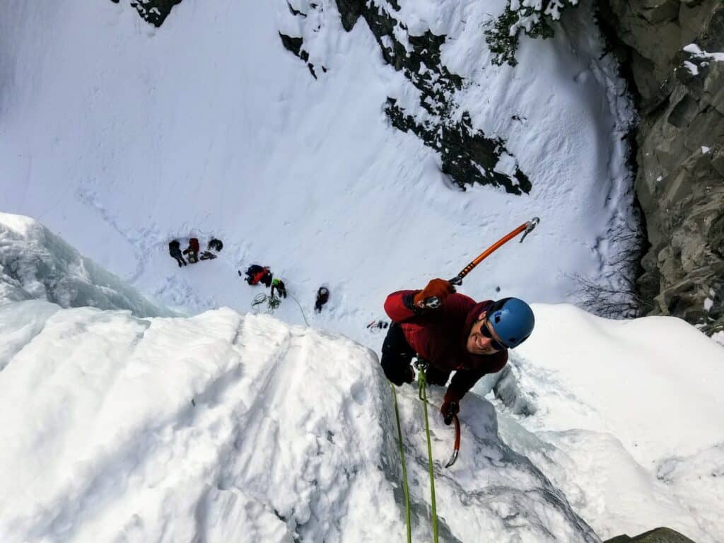 close up of a man reaching the summit of a ice climbing bouldering route