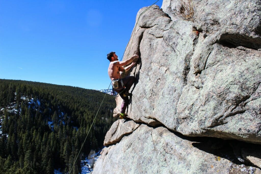 photo of a man scaling a rock formation using tips covered in the pro rock climber interview article.
