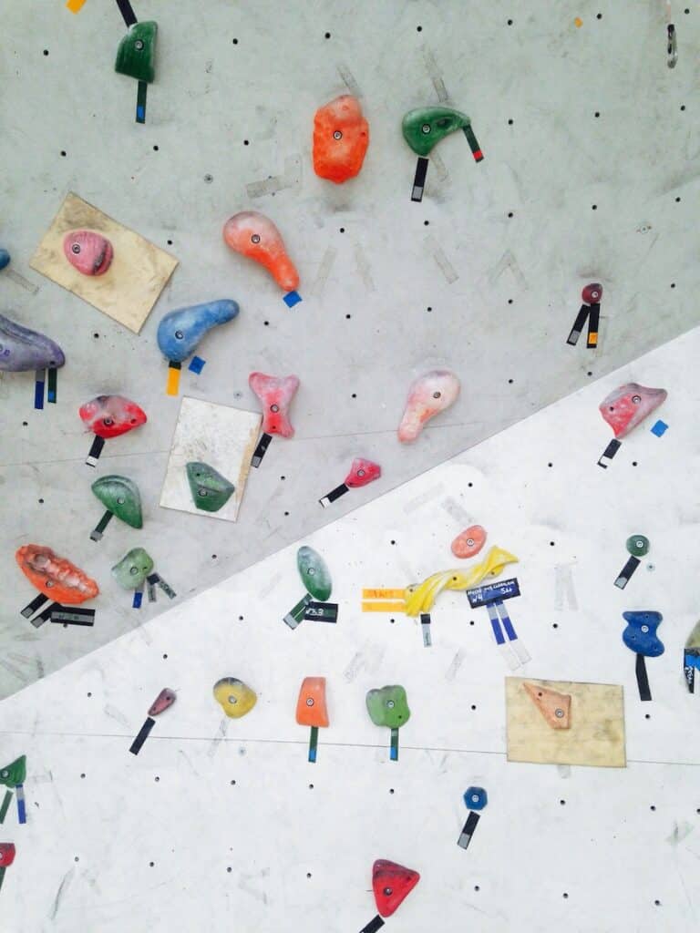 An indoor rock climbing bouldering wall featured in multiple colors