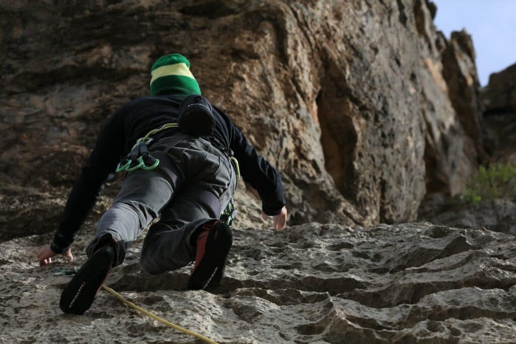 person climbing the face of a rock wall on one of the trad climbing routes