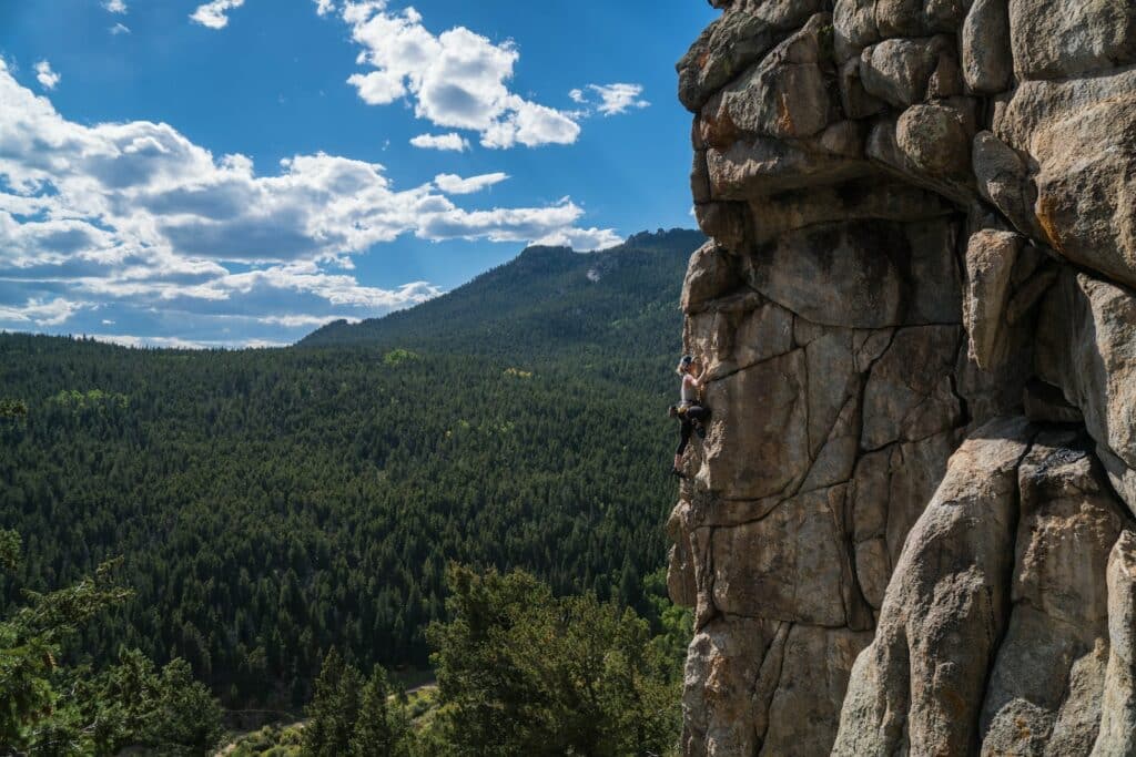 woman scaling rock formation showcasing trad climbing tope rope