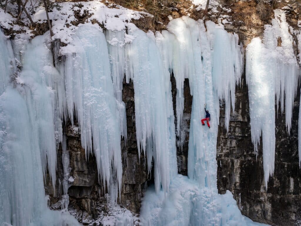 zoomed out shot of a person ice climbing soloing in an ice formation
