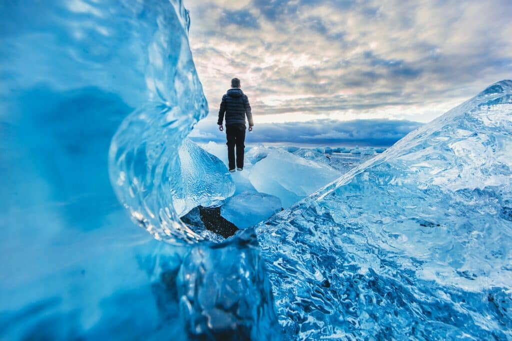 serene photo of man walking at the base of an ice formation, embodying getting the mindset for ice climbing documentaries