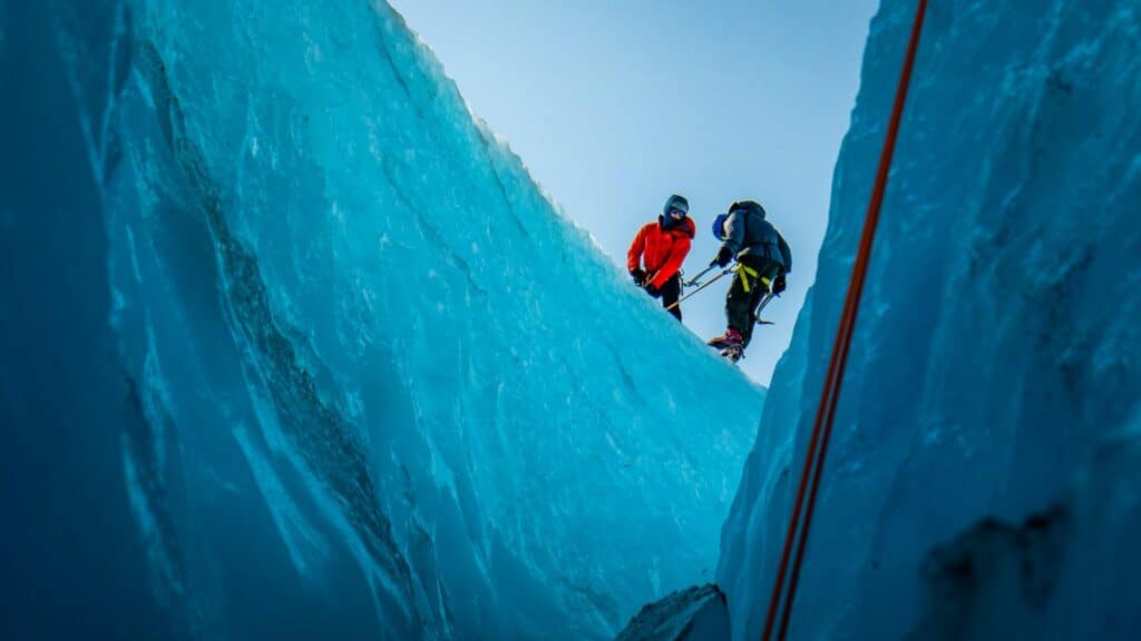 two people seen standing at the top of a ice formation discussing safety and techniques covered in the ice climbing for beginners article