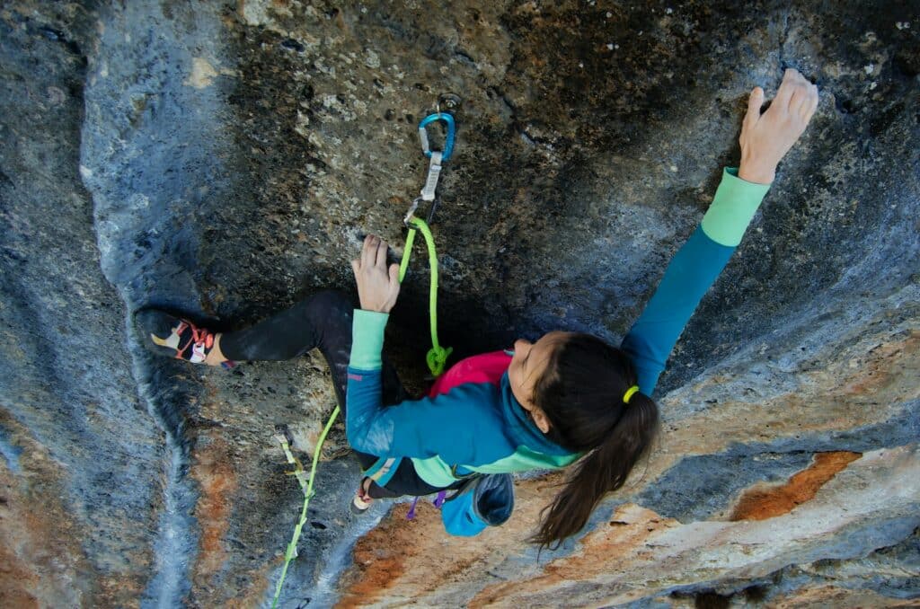 woman climbing a rock formation in one of the top rock climbing destinations for beginners