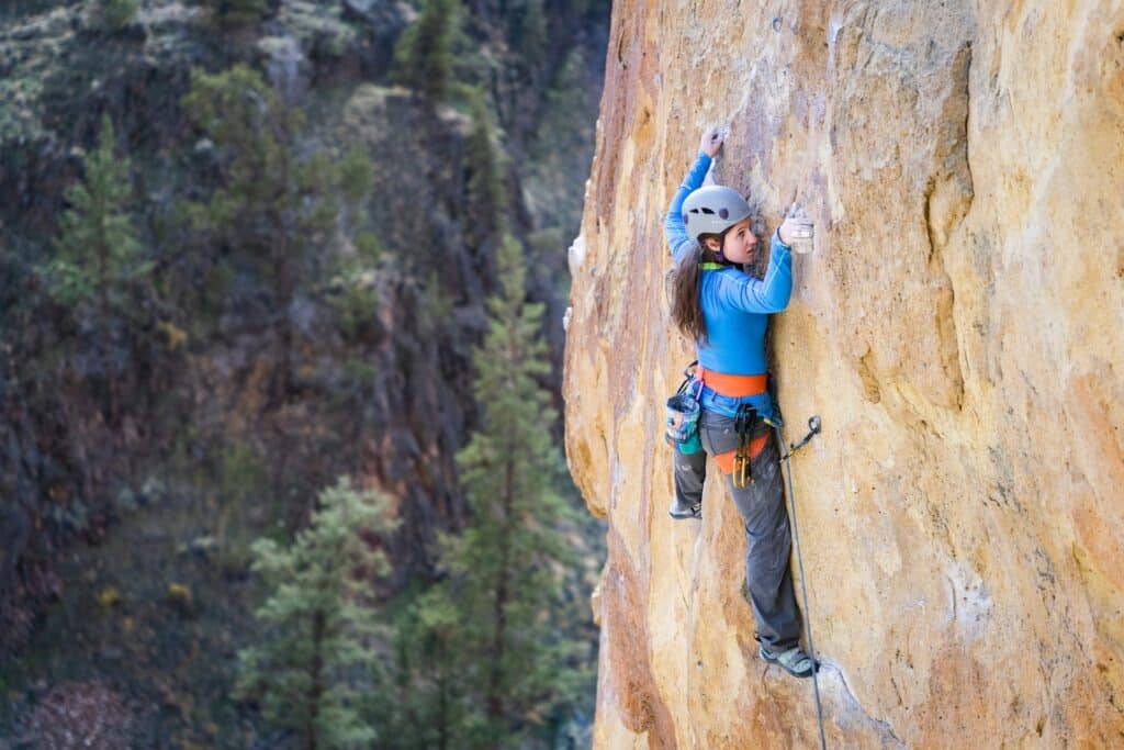 photo of a woman sport climbing an outdoor rock face as covered in the history of rock climbing article
